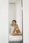 Retrato de mulher jovem atraente em lingerie sentada na cama — Fotografia de Stock