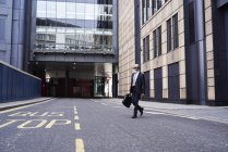 Великобританія, Лондон, старший бізнесмен з навушниками перетину вулиці — стокове фото