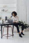 Mujer que trabaja en su oficina en casa, utilizando el ordenador portátil - foto de stock