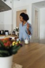 Mujer tomando un desayuno saludable en su cocina, escuchando música - foto de stock