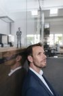 Empresario sentado en su oficina con su retrato 3D detrás de un cristal - foto de stock