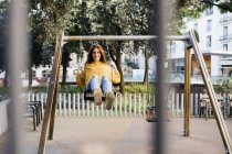 Spain, Barcelona, Red-haired girl on swing — Stock Photo