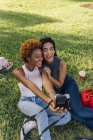 Two happy female friends taking an instant photo in a park — Stock Photo