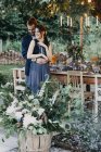 Felice sposa e lo sposo abbracciando a festivo apparecchiato tavola all'aperto — Foto stock