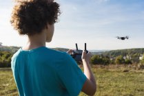 Junge steuert fliegende Drohne im Freien — Stockfoto