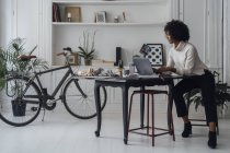 Femme travaillant dans son bureau à domicile, en utilisant un ordinateur portable — Photo de stock