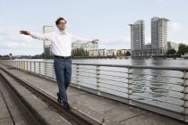 Германия, Берлин, бизнесмен балансирующий на рельсах на реке Шпрее — стоковое фото