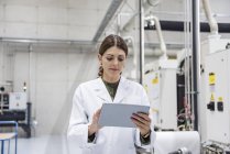 Woman checking manufacturing machines in high tech company, using digital tablet — Stock Photo
