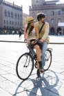 Italia, Bolonia, pareja joven en bicicleta viendo algo - foto de stock