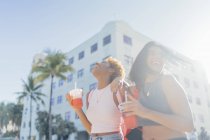USA, Florida, Miami Beach, dos amigas felices tomando un refresco en la ciudad - foto de stock