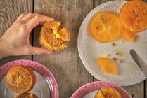 Woman's hand garnishing muffins with candied orange slices — Stock Photo