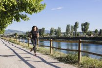 Sportive young woman running at the riverside — Stock Photo