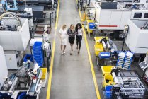 Tres mujeres con tableta caminando y hablando en el piso de la tienda de fábrica - foto de stock