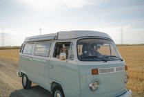 Pareja joven con gafas VR conduciendo caravana en paisaje rural - foto de stock