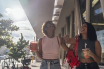 США, Флорида, Майами-Бич, две счастливые подруги за безалкогольным напитком в городе — стоковое фото