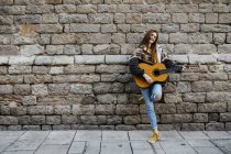 Red-haired woman playing the guitar in the city — Stock Photo