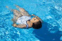 Giovane donna galleggiante sull'acqua in piscina — Foto stock
