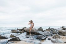 Jeune femme assise sur un rocher près de la mer — Photo de stock