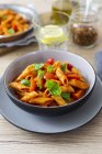 Top view of Penne pasta with tomato and basil leaves in bowls — Stock Photo