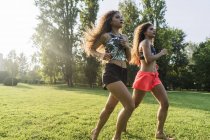 Twin sisters jogging together in a park at evening twilight — Stock Photo