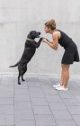 Giovane donna vestita di nero con il suo cane nero — Foto stock