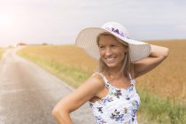 Усміхнена зріла жінка на віддаленому провулку країни влітку — стокове фото