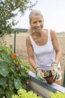 Portrait of smiling woman gardening at raised bed — Stock Photo