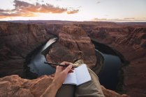 USA, arizona, colorado river, hufeisenbiegung, junger mann auf aussichtspunkt, notizbuch — Stockfoto