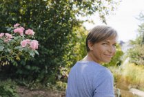 Portrait of smiling woman in garden turning round — Stock Photo