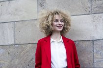Portrait of smiling blond woman with ringlets wearing red suit coat — Stock Photo