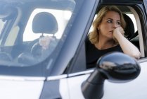 Скучная женщина, выглядывающая из окна машины — стоковое фото