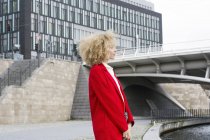 Germania, Berlino, giovane donna bionda con riccioli con cappotto rosso — Foto stock