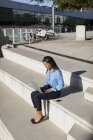 Businesswoman using laptop, sitting on stair — Stock Photo