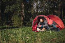 Homme campant en Estonie, assis dans une tente, buvant du café — Photo de stock