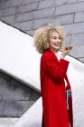 Портрет сміху білявої жінки з колечко носити червоне пальто і розмовляти по мобільному телефону — стокове фото