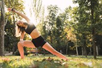 Fit jeune femme pratiquant le yoga dans un parc — Photo de stock