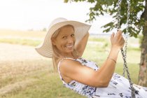 Щасливі зріла жінка на гойдалках у віддалених сільській місцевості — стокове фото