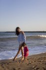 Mutter und kleine Tochter am Strand, Händchen haltend — Stockfoto