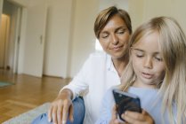 Madre e figlia guardando smartphone insieme — Foto stock
