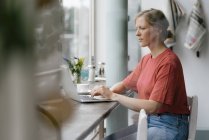 Junge Frau mit Laptop am Fenster eines Cafés — Stockfoto