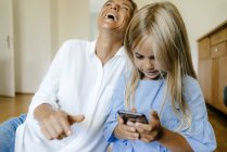 Ridendo madre e figlia guardando smartphone — Foto stock