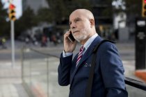 Senior businessman talking on cell phone in the city — Stock Photo