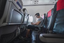 Uomo in aereo, con smartphone, cuffie — Foto stock