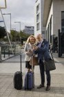 Uomo d'affari anziano e donna d'affari con bagaglio utilizzando i telefoni cellulari in città — Foto stock