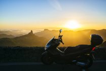 Spagna, Isole Canarie, Gran Canaria, motorino parcheggiato davanti al paesaggio montano al tramonto — Foto stock