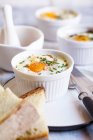 Oefs en cocotte (Individual baked eggs) with spinach, feta, bacon, eggs, and slices of bread — Stock Photo