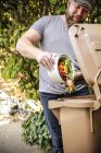 Зрелый человек бросает кухонные объедки в контейнер с биологическими отходами — стоковое фото