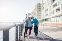 Amici sportivi che utilizzano smartphone al lungofiume — Foto stock