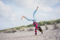 Mature woman having fun, cartwheeling on the beach — Stock Photo