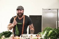 Вегетарианец держит морковку на кухне — стоковое фото
